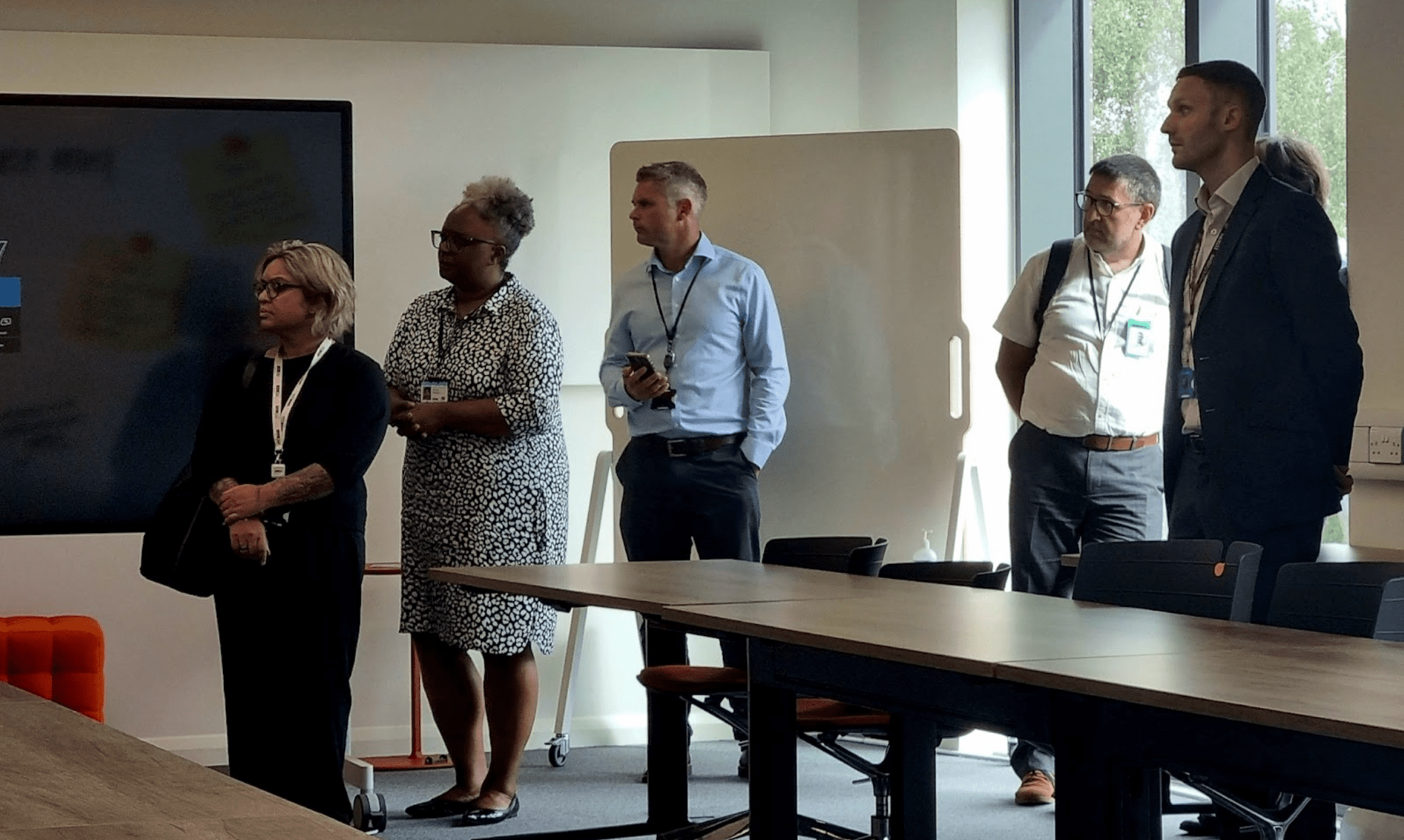 A group of colleagues standing together focused on an out-of-shot speaker