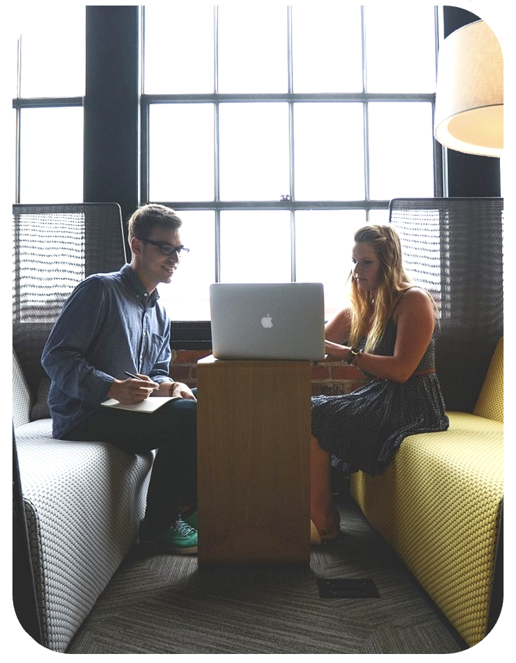 two colleagues sitting opposite eachother in a break-out zone looking at a laptop