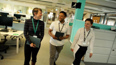 Three staff members walking through an office.