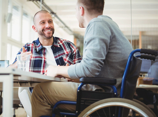 Two team members chatting together. One is a wheelchair user.