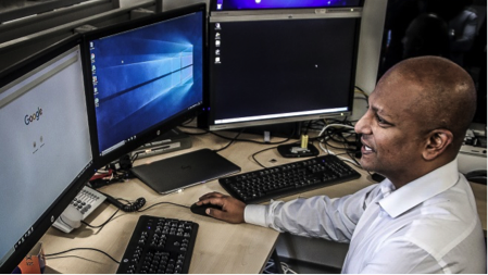 An NCA Operative sitting At a Desk With several Monitors