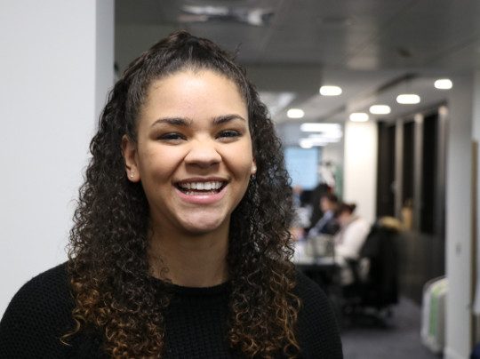 A Portrait Of A Counter Fraud Team Member, she is smiling and has dark curly hair