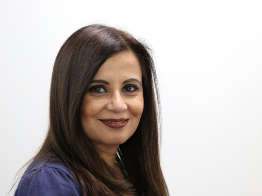 A Portrait Of Anita Jain, she has long dark hair and is smiling softly