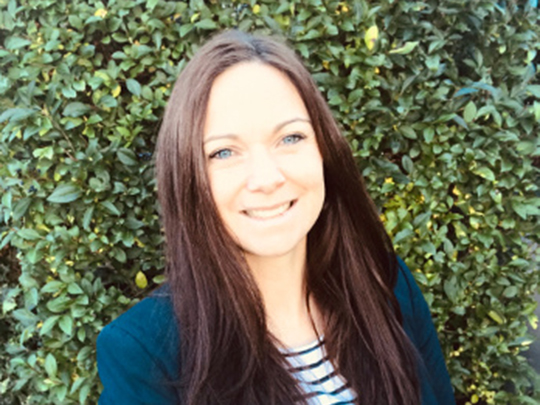 A photo Of Kate Lockett the Learning And Capability Lead. She has long brown hair and is wearing a striped top under a navy blazer.