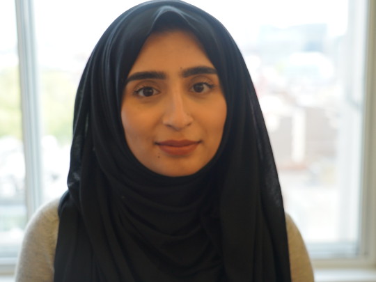 A Portrait Of Saira Ahmed, she is looking at the camera and her hair is covered.