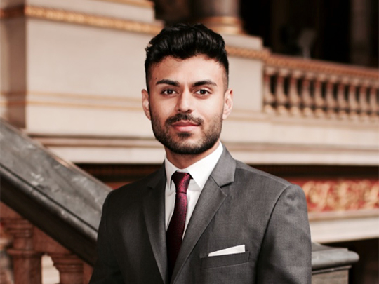 A photo of Ameer Patel, from the Joint Head Forced Marriage Unit Foreign And Commonwealth Office. He is dressed in a charcoal suit, with a burgandy tie and has a short beard.