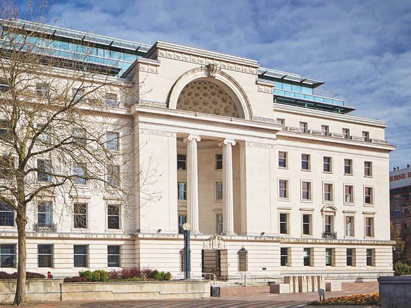 Baskerville House, a grand stone Art Deco building in Birmingham with a modern glass and steel extension on the roof.
