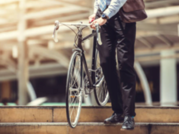 Man walking a bicycle down some steps. He is dressed smartly.