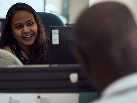 Two Government Communications Team Members chatting across their desks