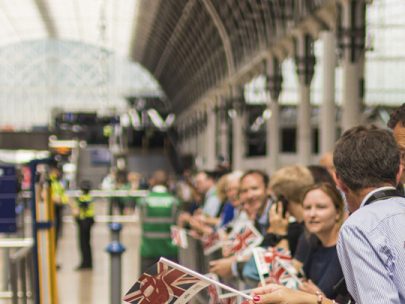 Photo of groups of supporters of Rail Opening at Paddington Station. They are holding mini union flags.