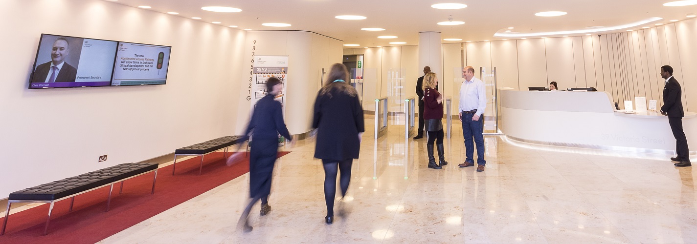 A photo of the Department Of Health And Social Care Office Foyer, it is a bright open space with a reception desk to the right