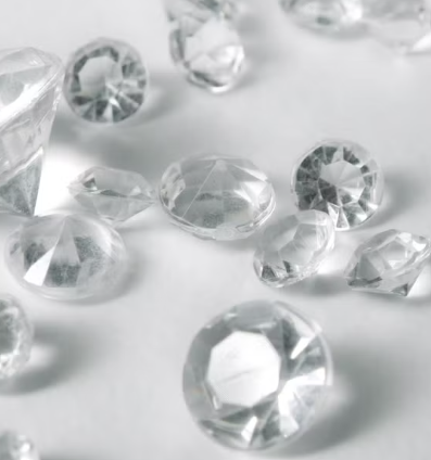 Image of diamonds scattered over a a white surface.