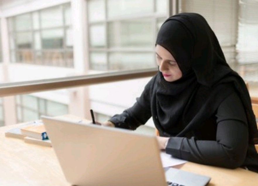 Person wearing hijab working at desk.