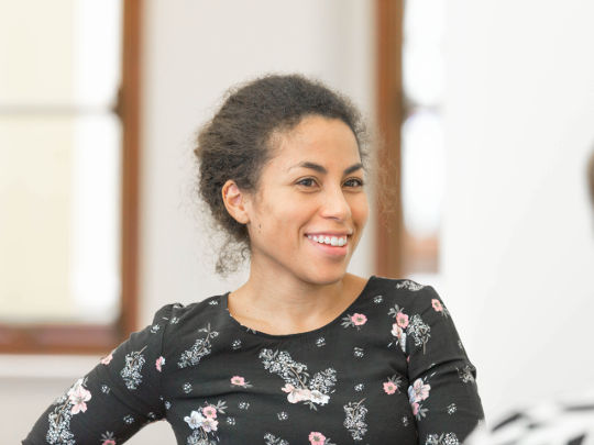 A Portrait of Hannah Dathorne at DCMS, she has dark hair tied in a bun, and is wearing a floral top