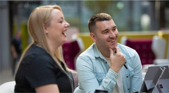 Hmrc colleagues laughing and chatting together in the office