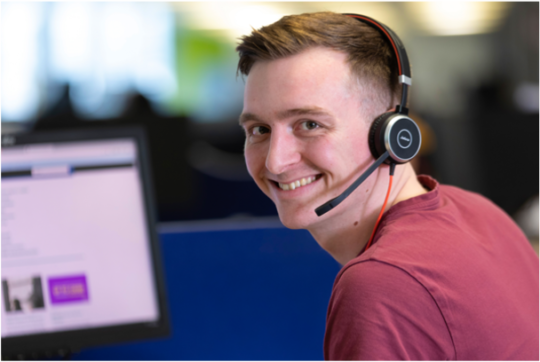 colleague working at a desk wearing a headset smiling at the camera