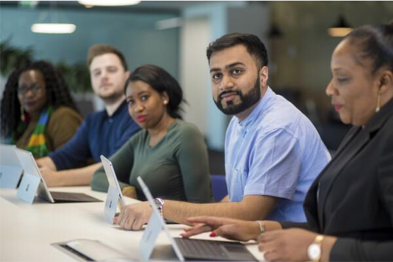 colleagues working at a shared desk space with laptops.