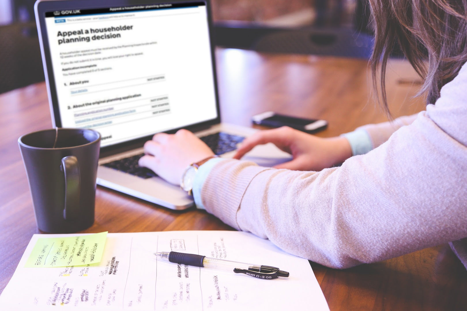 A person working on a laptop. The laptop screen shows a GOV.UK webpage titled "Appeal a householder planning decision".