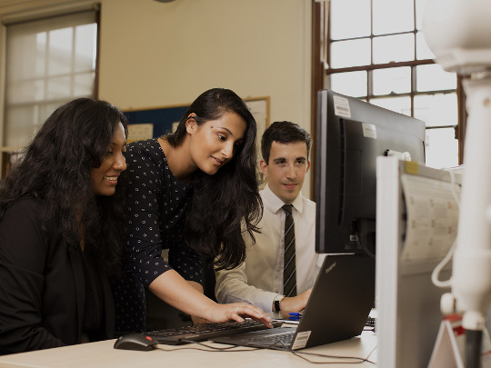 Three HM Treasury team members working collaboratively on a laptop