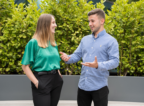 2 colleagues chatting and siling in an outside area