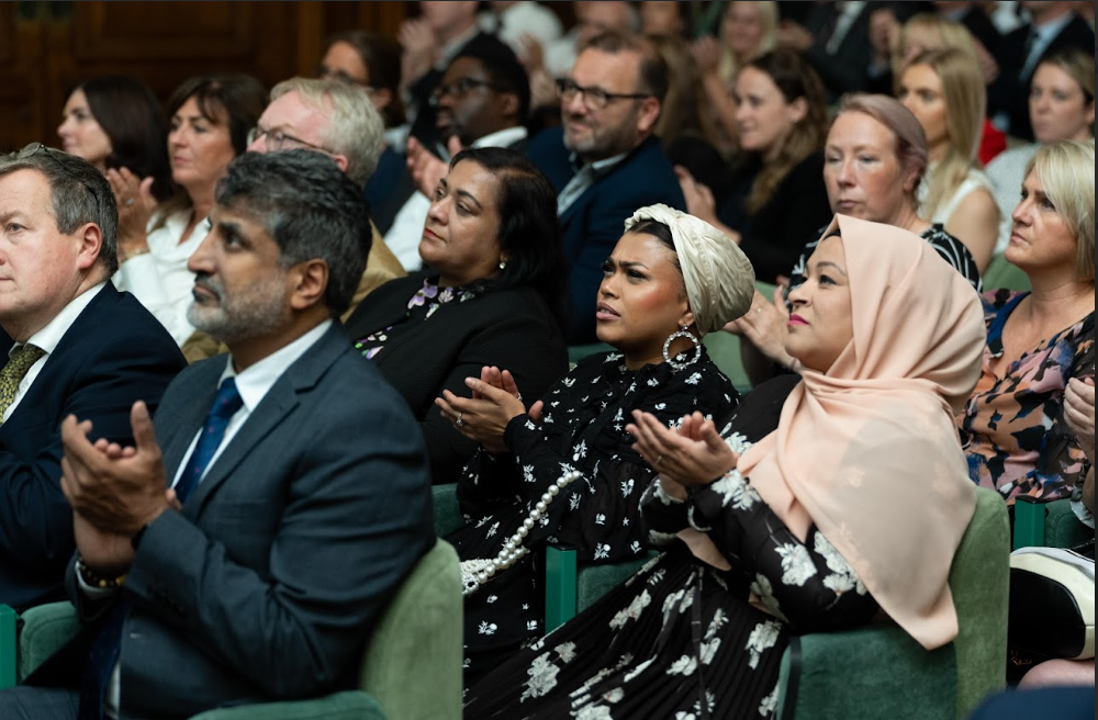 An auditorium of people applauding a speaker who is out of shot