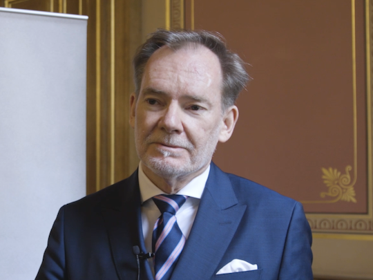 A Portrait of Crawford Falconer, he is wearing a navy blue suit.